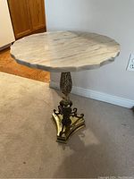 Full view of round marble top table with brass pedestal on carpeted floor