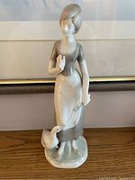 Front view of porcelain figurine showing lady standing with goose at feet
