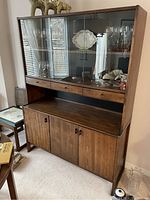 Front view of the MCM wooden cabinet showing the upper sliding glass doors with items inside, three wooden drawers, and lower two-door cabinet section.