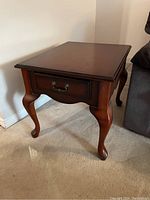 Front angle view of the wooden end table showing drawer and cabriole legs.