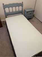 Blue vintage motorized bed with scalloped headboard and white mattress in carpeted room