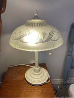 Side view of the vintage table lamp showing frosted glass shade with floral patterns and pull chain switch