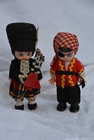 Two dolls, one dressed as a Scotsman holding bagpipes and another as a pirate with an eyepatch and bandana.
