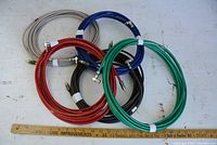 Five co-axial speaker cables in red, green, blue, black, and grey coiled with RCA connectors visible and a ruler to show scale.