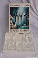 Six original Aalborg Akvavit long stem shot glasses in their original packaging displayed upright.