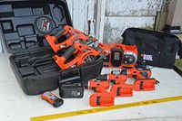 View of all items in the lot arranged on table including 2 power saws, 3 hand drills, 2 batteries, charger, stud finder, carrying case, and circular saw blade.