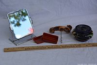 Overview photo showing all four items: tabletop mirror, brown box, wood handle corkscrew, navy ceramic jar with lid.