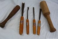 Full set of Dakstra wood carving tools and two wooden mallets on a white cloth background.