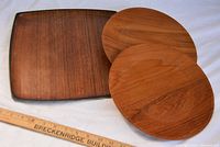 Two round teak wood plates and one square teak wood serving tray placed on white cloth background with a measuring ruler