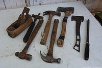 Full view of all 8 vintage hand tools arranged on a stained wooden surface, showing wear and rust