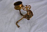 Side angle showing the two holders, a cylindrical cup holder and a circular segmented toothbrush holder, with mounting arm and base made of brass.