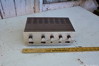 Front view of the vintage solid state amplifier showing control knobs and wood grain top cover with vent slots.