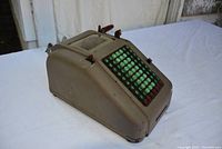 Side view of the vintage adding machine showing overall shape, color, and condition.