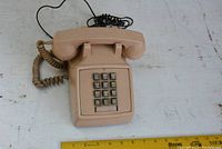 Front view of vintage taupe touch-tone house phone with numeric keypad and attached cords.