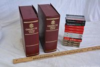 Two brown cassette library albums with gold text 'CASSETTE LIBRARY ALBUM' on spine, standing upright with a wooden ruler in front for scale.
