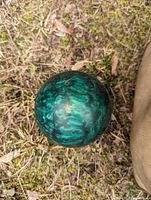 Close-up of a green marbled candlepin bowling ball placed on grass.