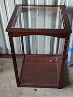 Photo showing front and side view of wood framed glass display box with lift-off top and brass knob.