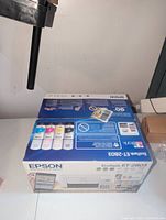 Photo of Epson EcoTank ET-2803 printer box showing included ink bottles and product details.