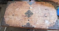 Top view of the closed chest showing its worn wood surface and metal decorative corner and center accents.