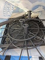 Photo of the black metal jewelry stand with multiple hooks and decorative curl details, placed on a fabric surface.