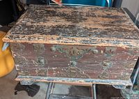 Front and side view of small antique wooden chest with metal studs and central handle showing wear and patina.