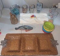 Photo showing the three-section tray with starfish, colorful ice cream bowls, measuring cups, jars with shells, towel with embroidered fish, decorative vase with blue stones, plastic cup, and sandcastle figurine.