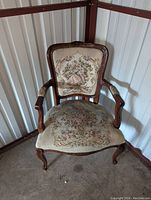 Front view of vintage wooden armchair showing carved wood frame and embroidered seat and back upholstery