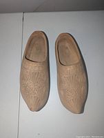 Top view of the pair of wooden clogs showing the carved geometric and floral pattern details on their surface.