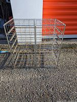 Metal wire square storage rack shown outdoors, with open compartments for holding papers, magazines, or comics.