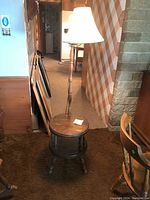 Front view of first mid-century modern lamp table showing round wood tabletop and lamp with white fabric shade. Photo taken for full item view.