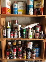 Wooden shelving with three shelves filled with various cans and bottles of wood finishing and maintenance products.