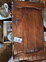 Top view of rustic wooden coffee table showing wood grain and knot details, with a small tag on the surface.