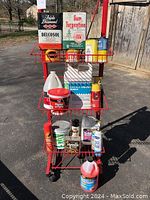 Red metal rack holding assorted household products including solvents, bug killers, cleaning sprays, and powders