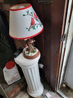 View of the pedestal table with one cardinal bird lamp on top, showing detailed bird and branch base and matching lampshade.