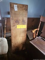 Wooden game board table vertically positioned showing cribbage scoring holes and worn natural wood finish with visible grain and knots. Tagged with auction identification.