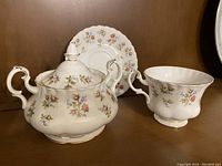 Clear image of the full set showing sugar bowl with lid, teacup, and saucer, all featuring floral patterns and gold trims.