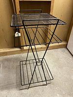 Side view of the standing metal organizer showing the mesh top shelf and two wire lower shelves with the triangular frame.