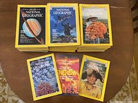 Magazines stacked showing front covers with subjects including an astronaut underwater, a person holding a large bunch of orange mushrooms, a Saturn image, and children in native attire.