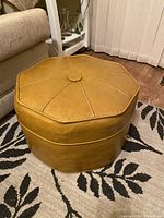 Side angle of the mustard yellow faux leather ottoman hassock showing the octagonal shape and stitched panel detail.