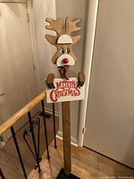 Full view of wooden standing reindeer Christmas decoration with 'Merry Christmas' sign held in front.