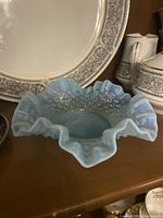 Side angled view showing the blue glass candy dish with ruffled edge and hobnail texture on the inside base.