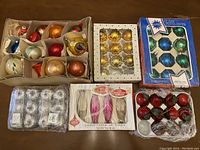 Full lot top-down view showing multiple boxed and loose vintage Christmas ornaments, various colors and styles