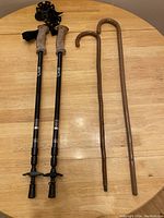 Walking poles and wooden canes laid out on wooden table showing handle details and overall condition
