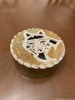 Top and angled view of round smudge bowl with wolf motif lid showing carved stone and scalloped edge.