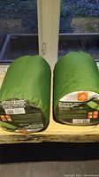 Two green self-inflating camping mats rolled and stored in compact size.