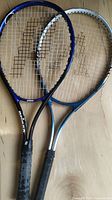 Two tennis racquets laid side by side showing frames and string pattern, indicating brands Prince and Atomica with worn grips.