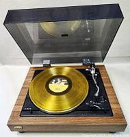 Turntable with golden vinyl on platter and dust cover open