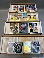 Four open boxes filled with hockey cards arranged neatly, showing various player cards from different sets including rookies and holographic cards.