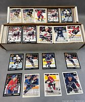 Two boxes filled with hockey cards including players in action on the ice wearing various team uniforms from Pinnacle and Upper Deck series.