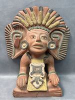 Front view of terracotta Mayan Corn God Hunahpu statue showing intricate headdress with corn and feather motifs, face, and chest ornamentation.